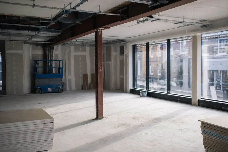 An empty commercial floor mid-refurbishment with steel beams and a scissor lift